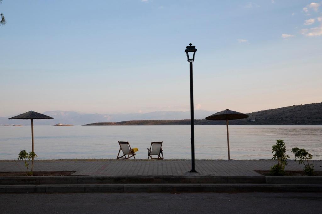 Pebble beach with straw umbrellas in front of Nerissa Itea